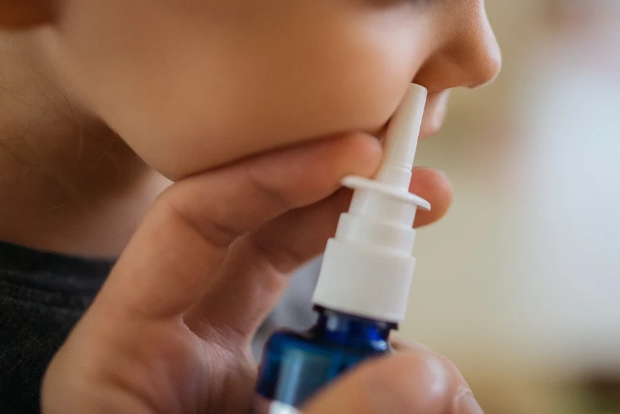 Adulte tenant un spray nasal sous la narine d'un enfant