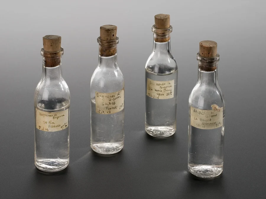 Quatre anciens flacons d'échantillons d'eau, bouchés au liège et étiquetés