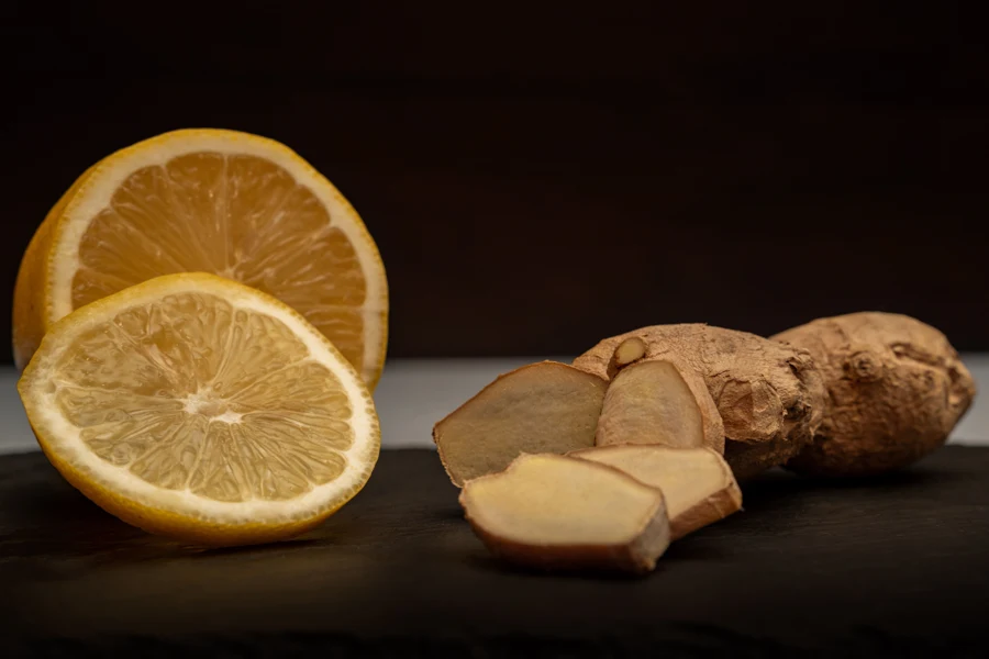 Demi-citron, citron entier et tranches de racine de gingembre posés sur une ardoise